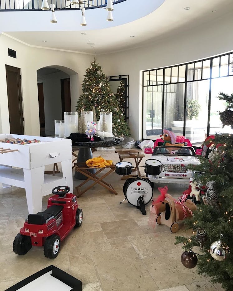 A room in Kourtney Kardashian's house with Christmas presents: two car toys, a drummer kit, plushies