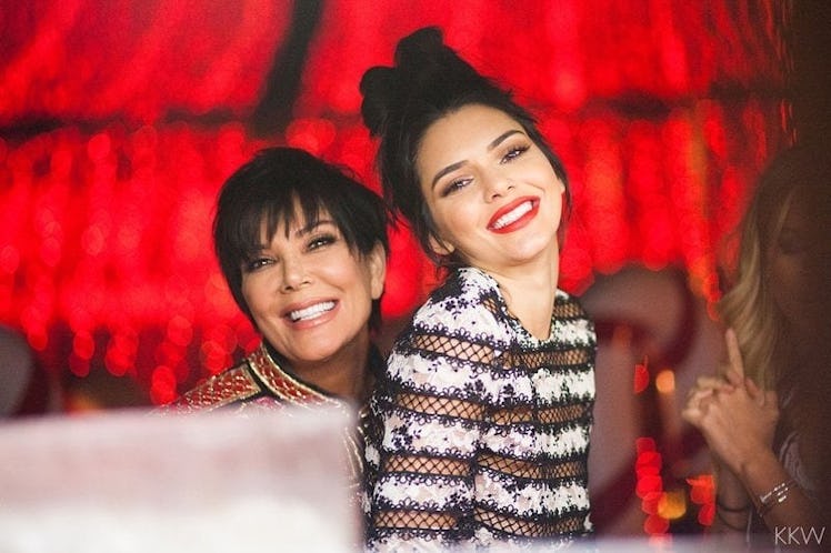 Kris Jenner and Kendall Jenner smiling in matching black-white dresses at a Christmas party