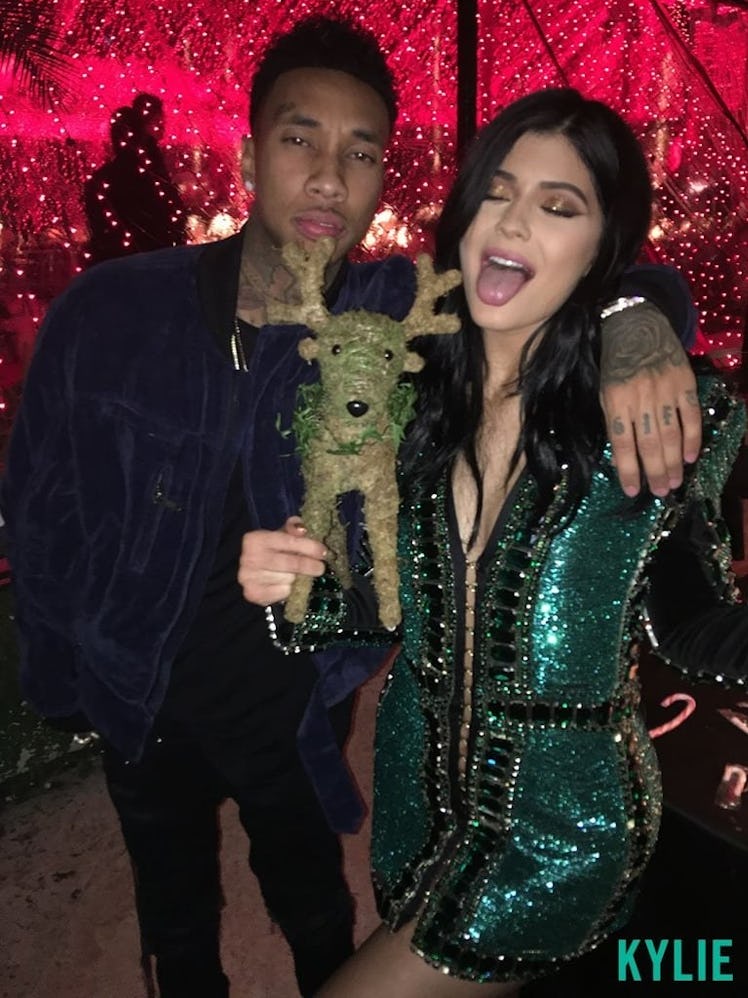 Tyga and Kylie Jenner posing with a statue Christmas deer toy at a Christmas party