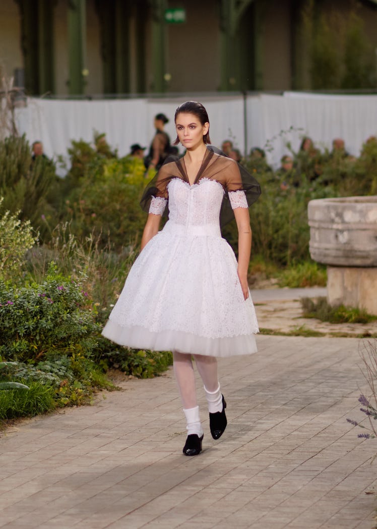 Kaia Gerber in a white lace dress walking at the Chanel Couture Spring 2020