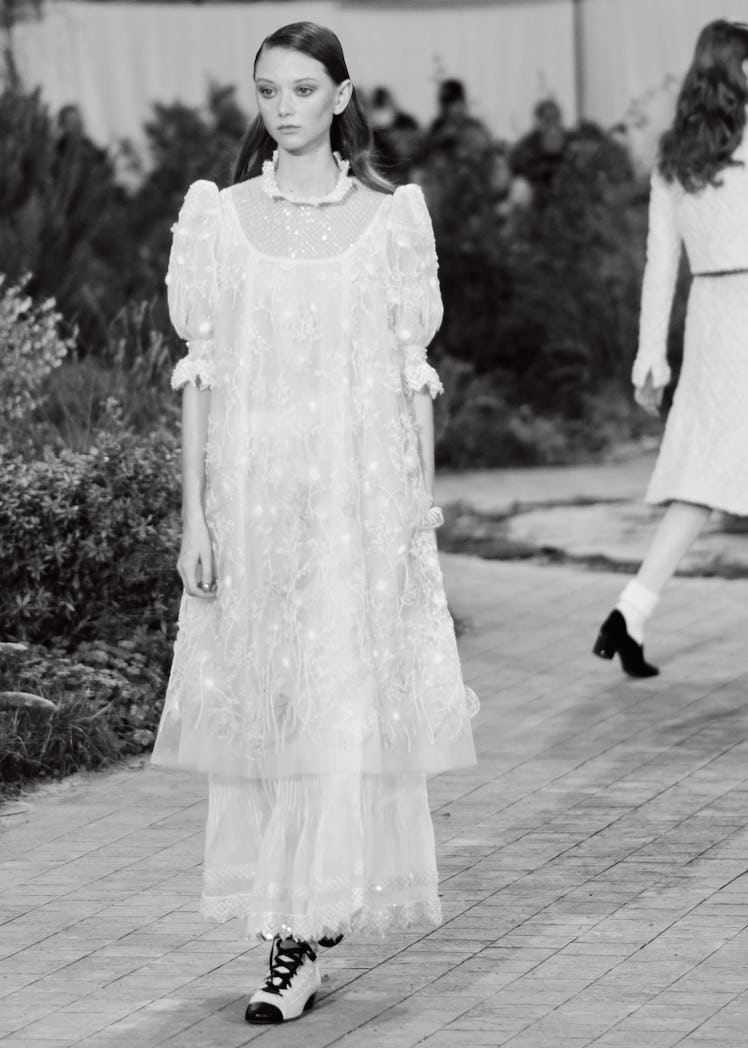 A model walking in a long white lace dress at the Chanel Couture Spring 2020 runway