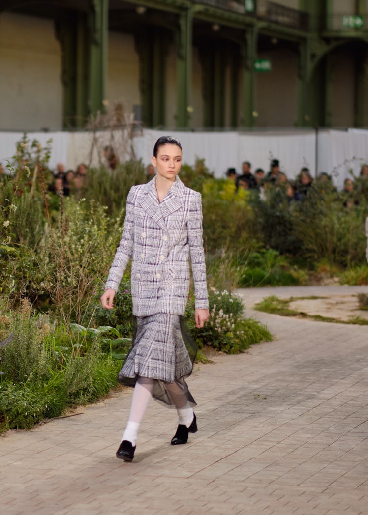 A model walking in a black-white tweed blazer and skirt at the Chanel Couture Spring 2020 runway