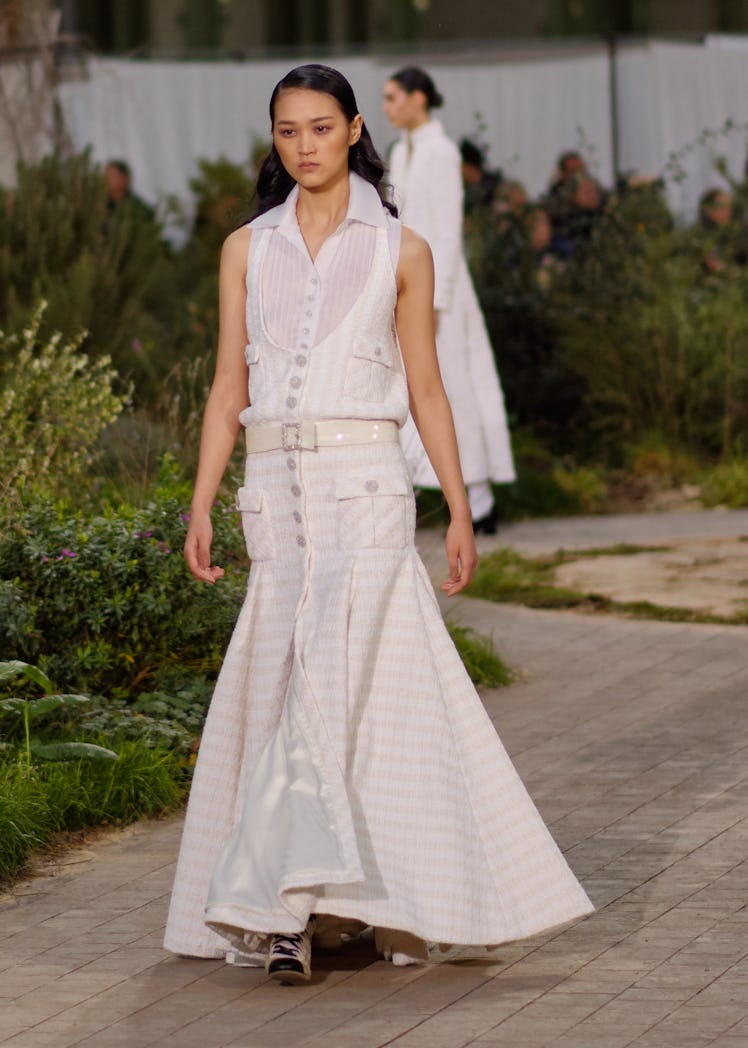 A model wearing a white top and a cream dress at the Chanel Couture Spring 2020 runway