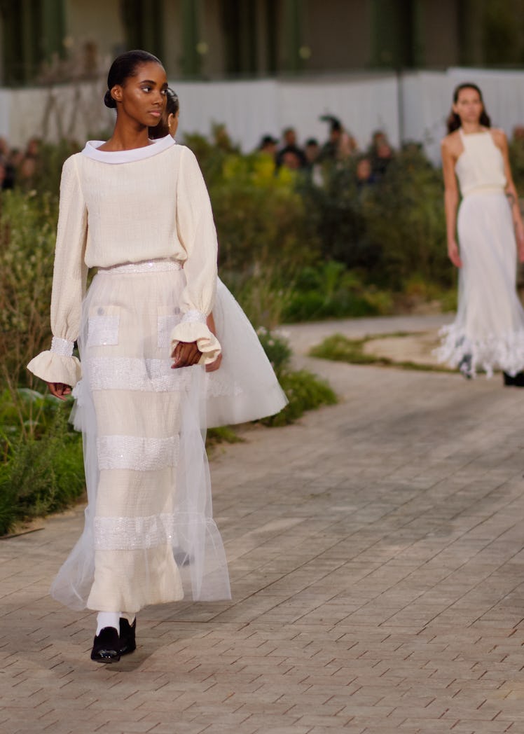 A model wearing a cream-white top and skirt at the Chanel Couture Spring 2020 runway
