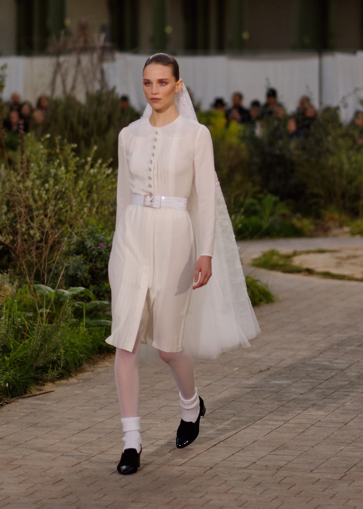 A model wearing a cream dress and a matching veil at the Chanel Couture Spring 2020 runway