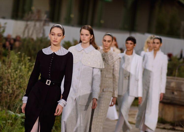 Models walking in white outfits with Gigi Hadid in a black dress in the front at the Chanel Couture ...