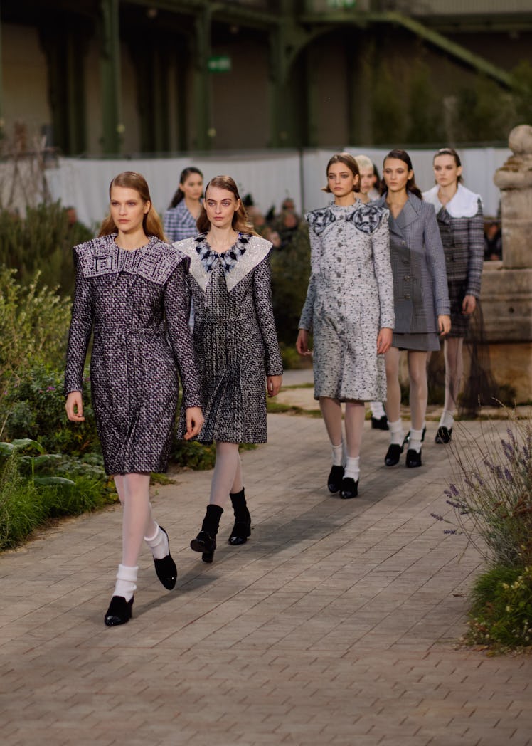 Several models walking in a line, while wearing grey tweed outfits at the Chanel Couture Spring 2020...