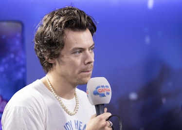 Harry Styles talking on the microphone wearing pearls, backstage in the on-air studio at London’s O2...