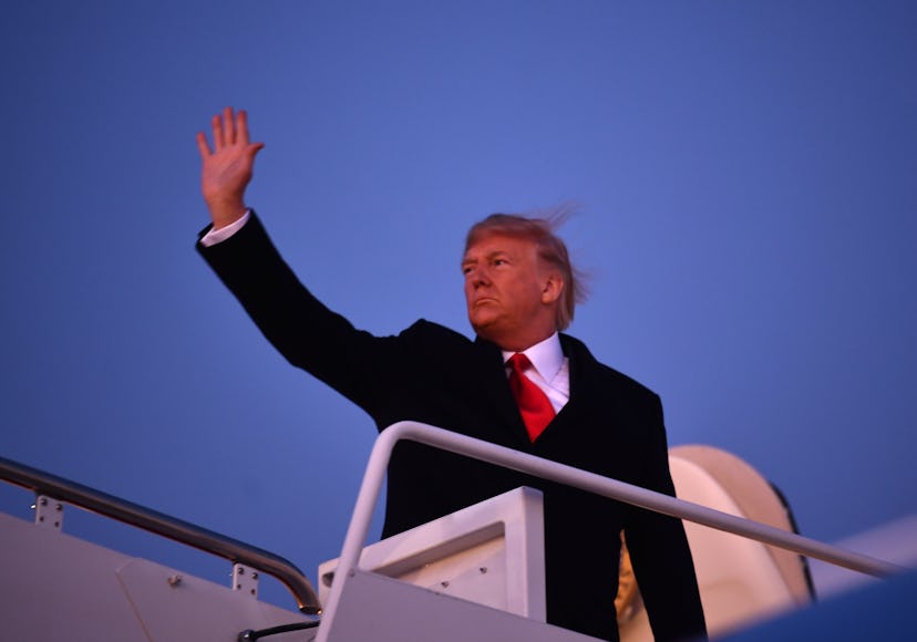 Donald Trump waving to the onlookers as he descends the airplane steps.
