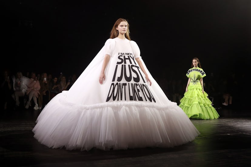 A model posing in a white gown with "I'm not shy, I just don't like you" text at a Haute Couture col...