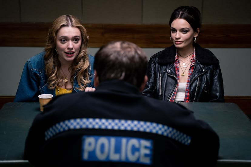 Aimee Lou Wood and Emma Mackey talking to a police officer at the station in Sex Education