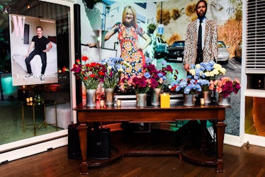 Seven vases with flowers in different red, blue, white and burgundy on a wooden table at W Magazine’...