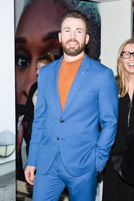 Chris Evans in a blue suit and an orange shirt standing and smiling at W Magazine’s Best Performance...