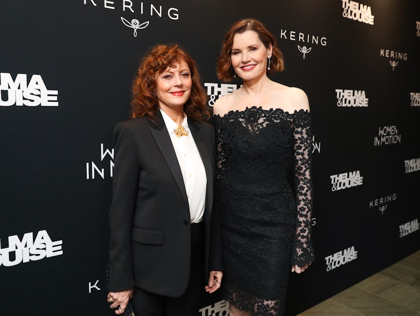 Susan Sarandon in a white shirt an black suit  and Geena Davis in a black lace dress at a red carpet...