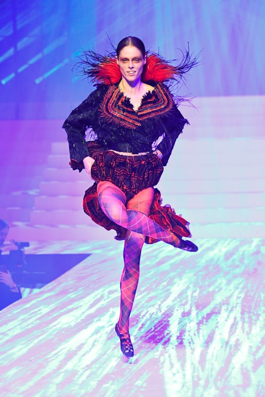 Coco Rocha in a red-black coat dress posing on the runway during Jean Paul Gaultier's last couture s...