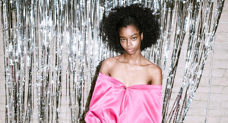 A model in a pink silk shirt with the shoulders exposed and matching pink pants