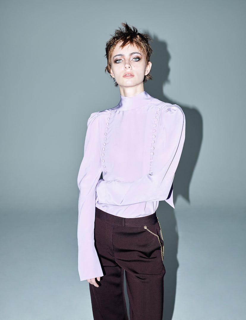 A model wearing a lavender blouse and brown pants while having eyebrows done by Gwyneth Paltrow's ey...