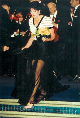 Princess Caroline of Monaco in a white-black top and a black skirt holding flowers