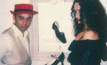 Christian Louboutin in a white shirt, cream blazer and a red hat and Farida Khelfa in a black top