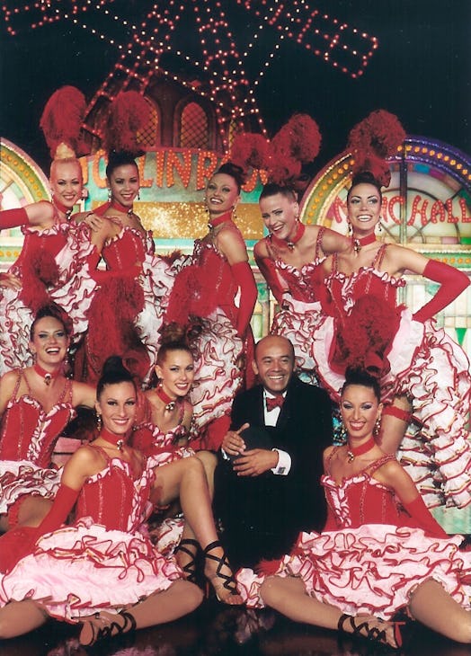 Christian Louboutin posing with a group of showgirls in white and red