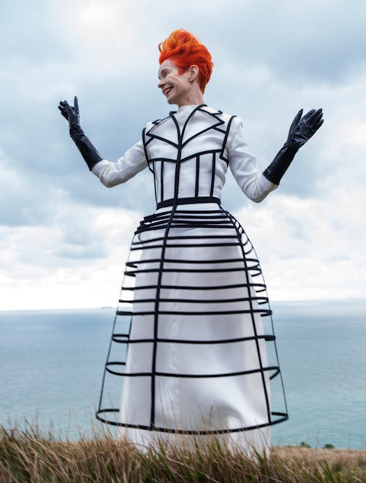  Sandy Powell posing in a white and black Aganovich overcoat and dress and black Versace gloves