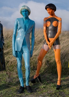 Four models posing in black, blue, orange-black and yellow outfits by Sandy Powell