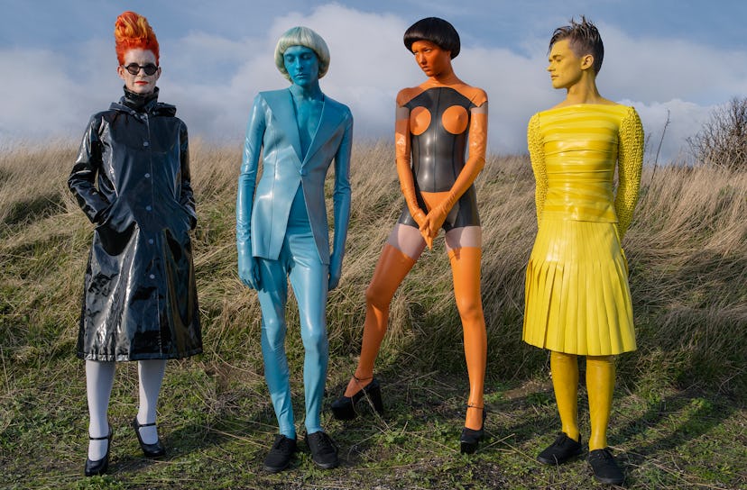 Four models posing in black, blue, orange-black and yellow outfits by Sandy Powell