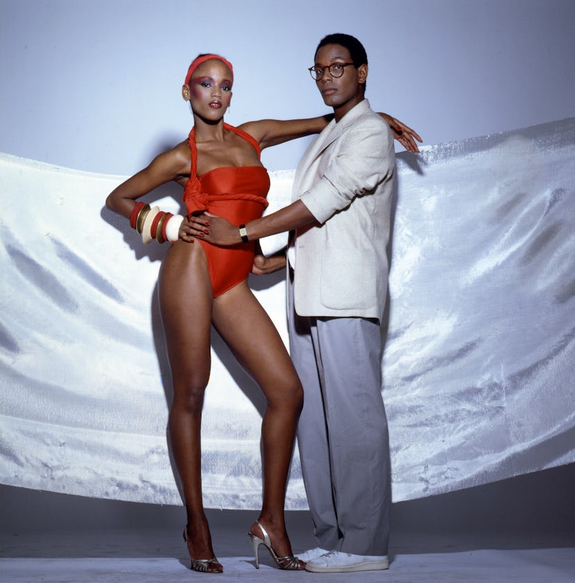 Designer Willi Smith in a white blazer and grey pants next to a model in a red bathing suit