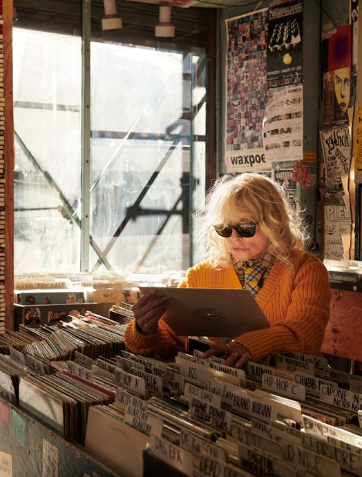 Debbie Harry in a record store wearing a yellow sweater, plaid shirt, plaid tie by Marc Jacobs and b...