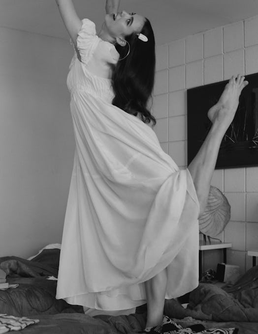 Margaret Qualley dancing on a bed in a white Chloé dress