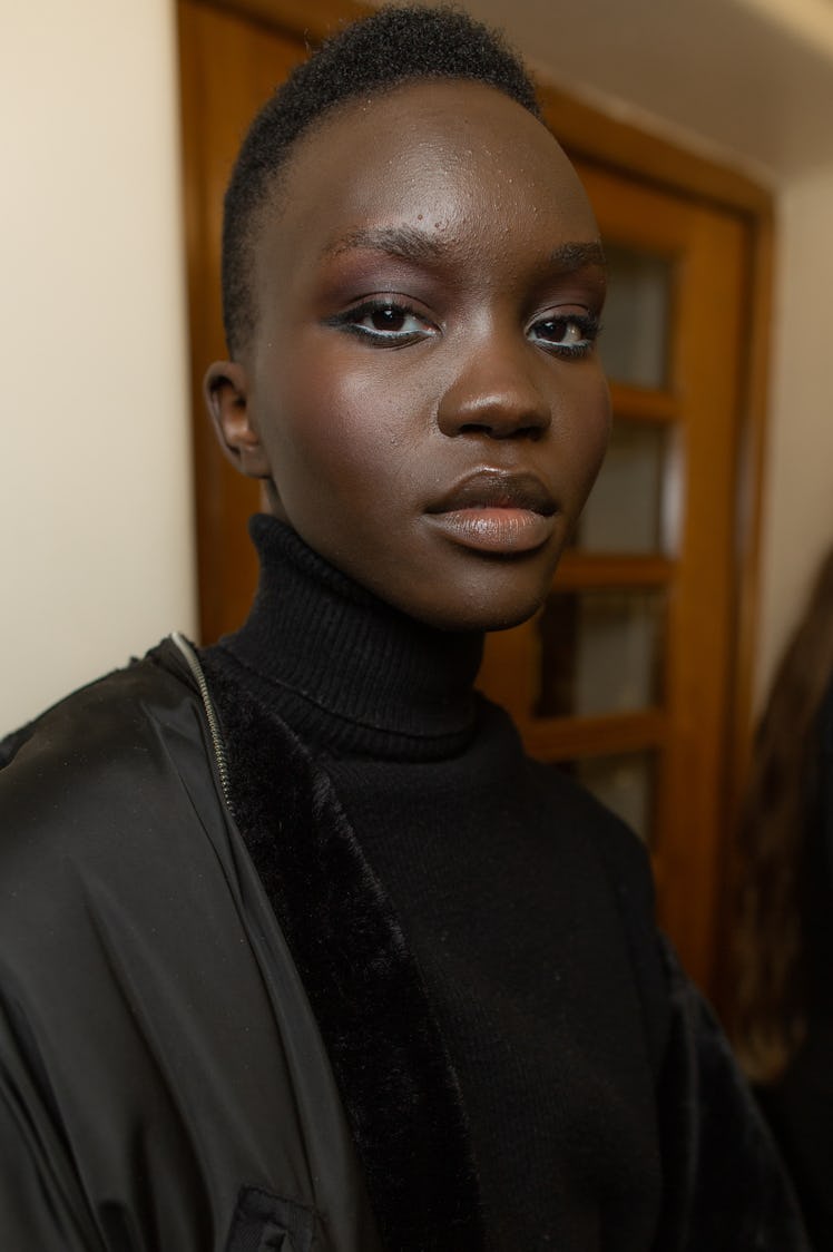 A close-up portrait of a model in a black jacket and turtleneck at Richard Quinn‘s fall collection 