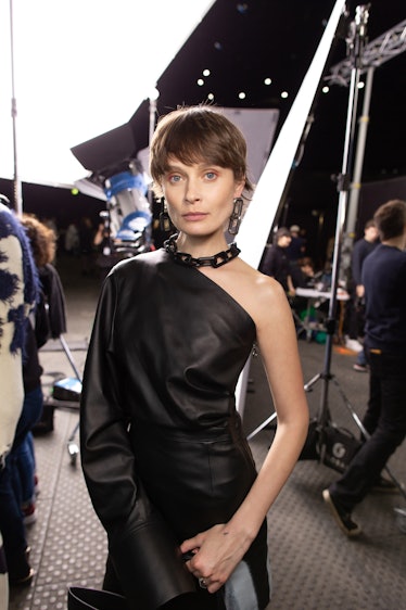 A model in a black leather one shoulder dress backstage at Off-White