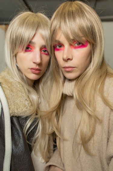 Two models with blonde wigs and pink eyeshadow backstage at the Matty Bovan fashion show