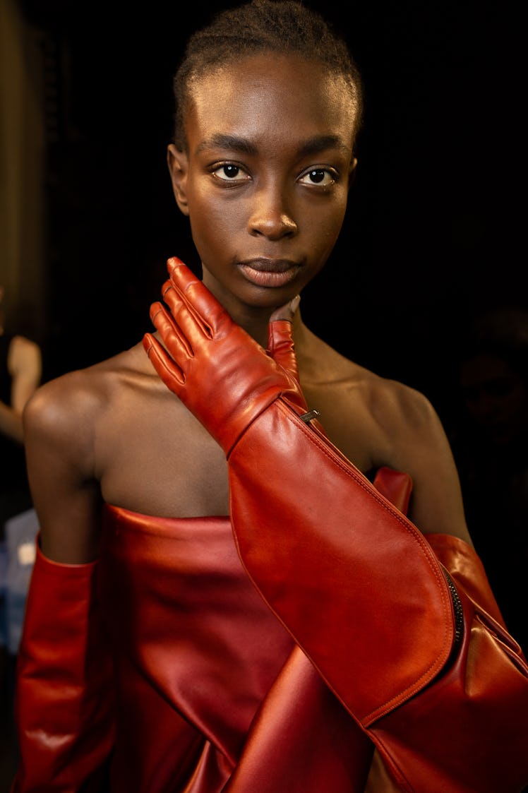 A model in a red leather dress and gloves backstage at the Rick Owens fashion show
