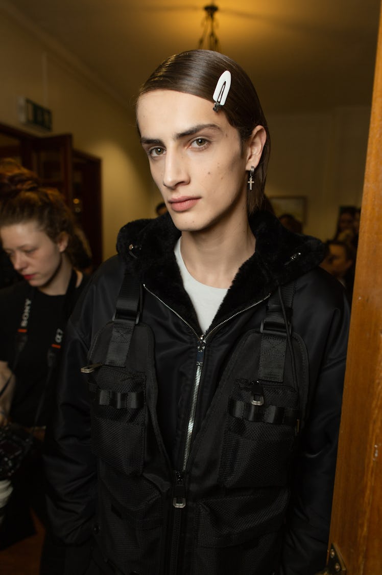 A model in a white shirt and a black jacket backstage at Richard Quinn‘s fall collection 