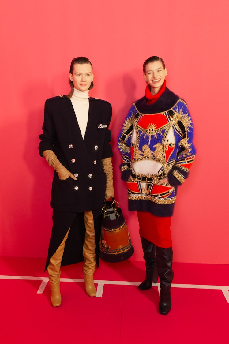 A model in a black coat and a model in a black-red-white dress at Balmain Fall 2020