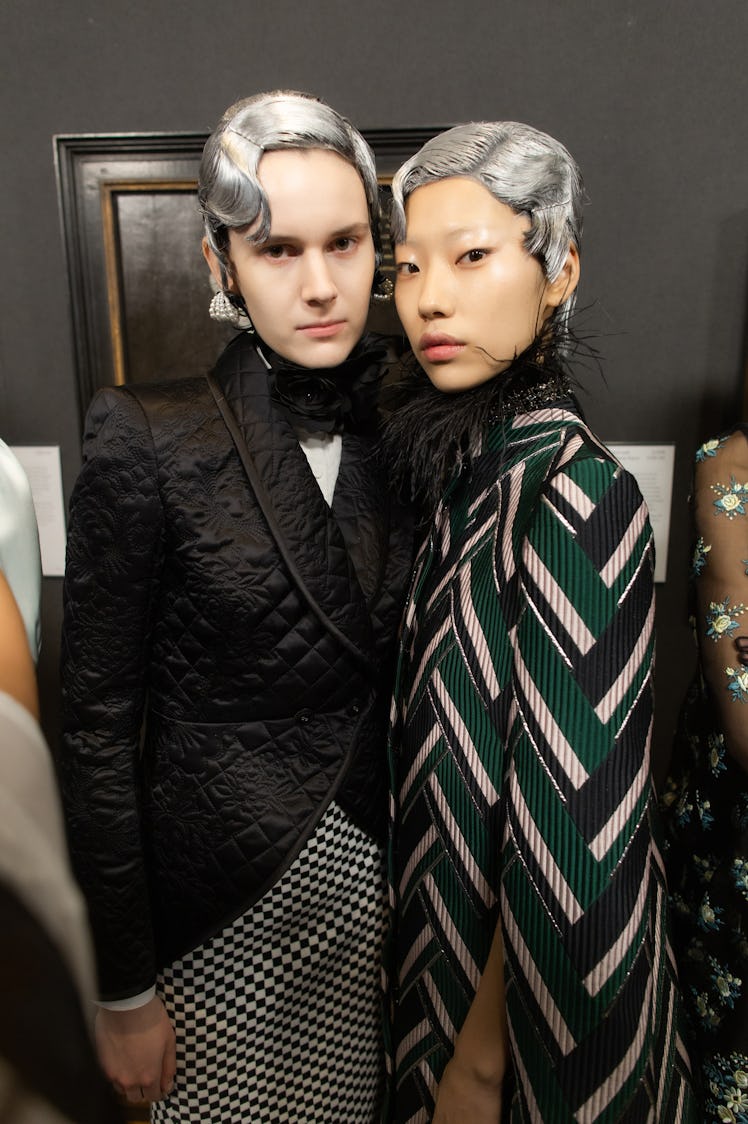 Two models posing for a photo in Erdem Moralıoğlu outfits topped with silver hairstyles