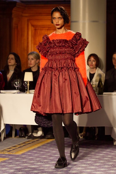 A model wearing an orange sweater and a red dress at Molly Goddard’s London Fashion Week Show