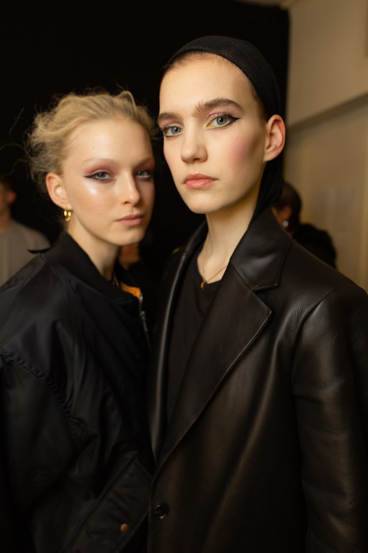 A model in a black bomber jacket and a model in a black blazer backstage at Richard Quinn‘s fall col...