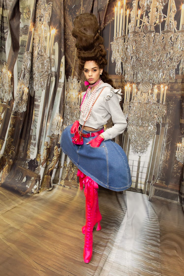 A model in a blue denim skirt, grey top and pink boots backstage at the Moschino Fall 2020 show