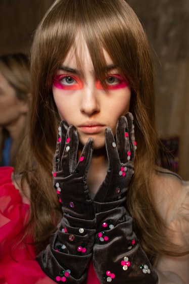 A model with pink-orange eyeshadow wearing black velvet gloves with sequins backstage at the Matty B...