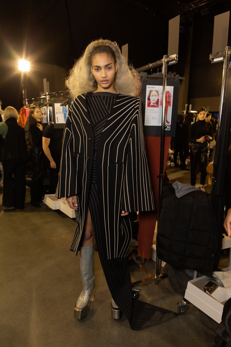 A model in a black coat with white stripes backstage at the Rick Owens fashion show