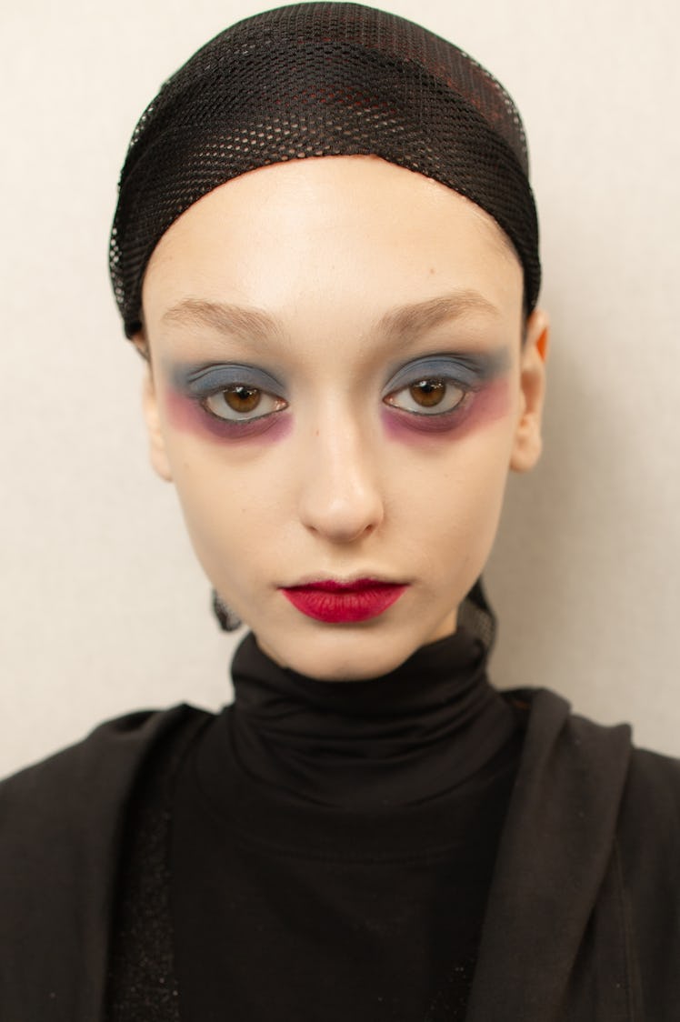 Closeup of a female model with white makeup and a black cap