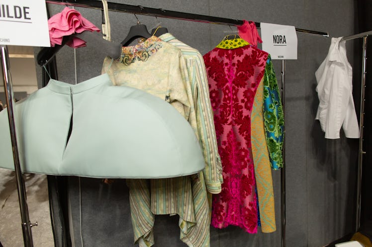 A grey skirt, a beige dress and a pink, yellow and green floral dress on a rack backstage at the Mos...
