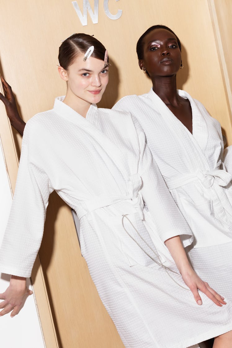Two models posing backstage in white robes at Tom Ford's fashion show