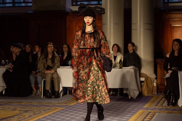 A model wearing a brown floral coat dress and a black hat at Molly Goddard’s London Fashion Week Sho...