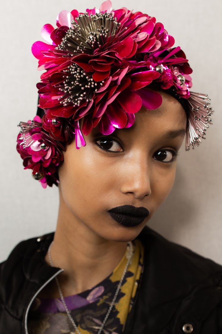 A female model posing while wearing a rose flower shaped cap