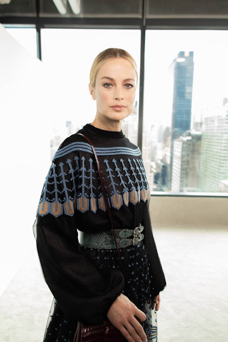 A blonde female model posing for a photo while wearing a black sweater