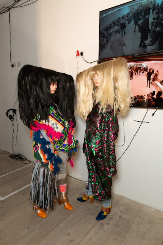 Two models with large wigs in backstage at Matty Bovan