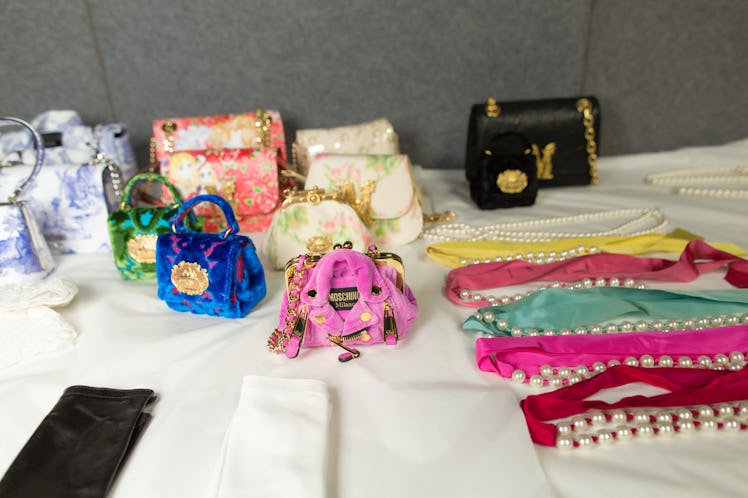 Pink, blue, orange and cream bags and satin chokers on a white surface backstage at the Moschino Fal...